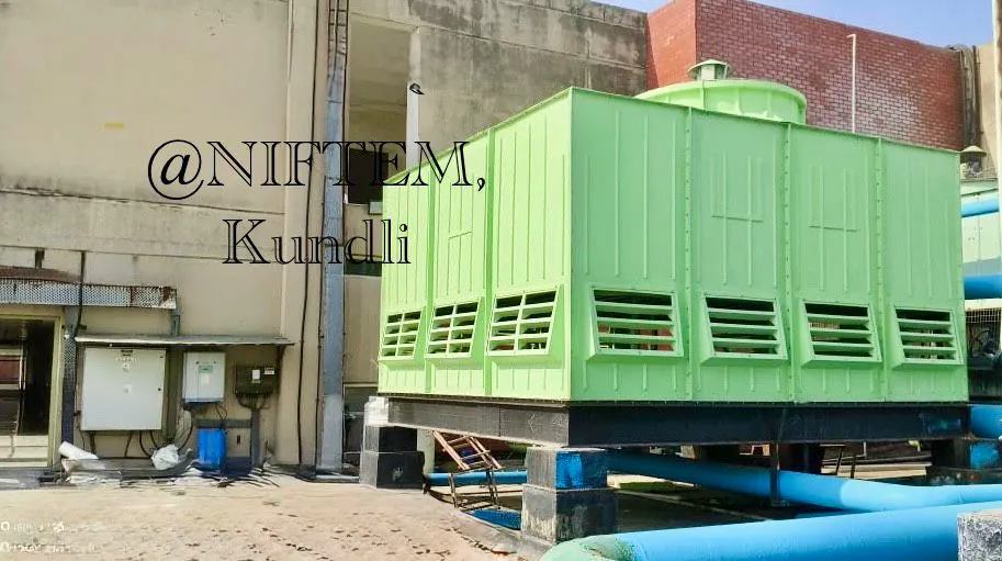 Green multi-cell FRP cooling tower with louvred air inlets and blue header piping at NIFTEM Kundli